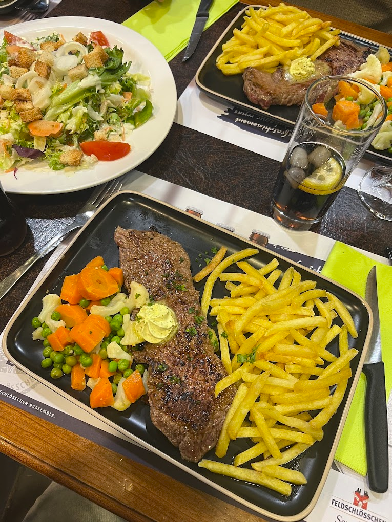 Steak grillé servi avec légumes, frites et salade César.